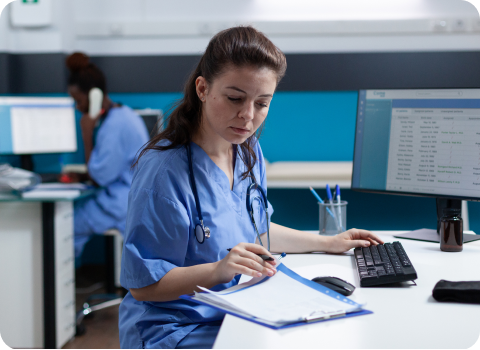 Nurse working at a computer with a clipboard